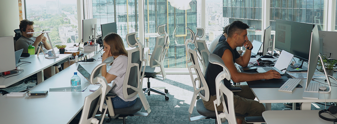 Product team multitasking across devices, reviewing tasks and refining projects in a modern office setting.