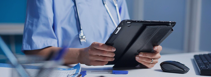 Lekarz korzysta z tabletu, aby uzyskać dostęp do elektronicznej dokumentacji medycznej i zdalnie koordynować opiekę nad pacjentem.