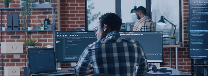 Tech specialist focused on coding in an open-plan office environment with digital workstations