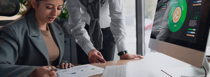 ESG analysts review social, governance, and environmental data together usingprinted report and digital dashboard.