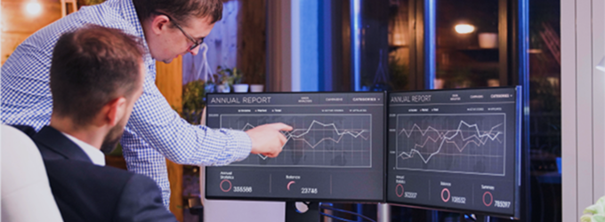 Financial analysts collaborate on yearly performance data, analyzing trends for executive decision-making