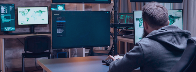 IT analyst monitoring global network dashboards on a multi-screen workstation in a security operations center