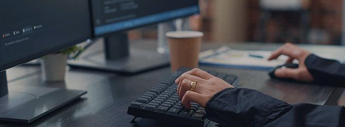 Software developer coding at a dual-monitor workstation in a modern office environment