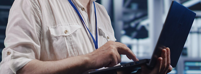 Tech team member managing hardware and troubleshooting issues using a laptop in a data center