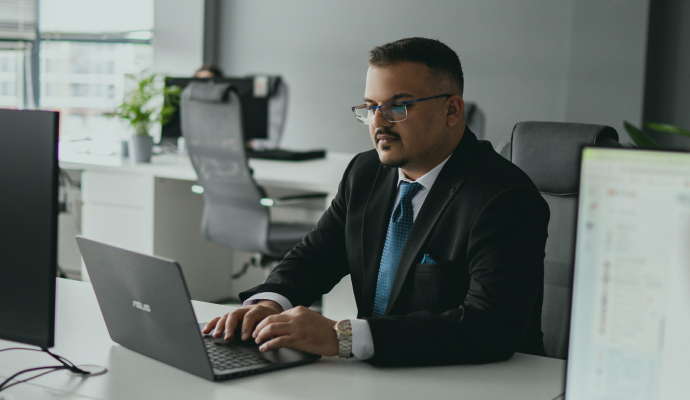 Grupo de profesionales inclinados para revisar contenidos digitales en ordenadores portátiles, mostrando el trabajo en equipo y la toma conjunta de decisiones.