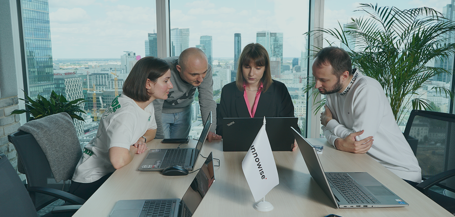 Grupo de profesionales inclinados para revisar contenidos digitales en ordenadores portátiles, mostrando el trabajo en equipo y la toma conjunta de decisiones.