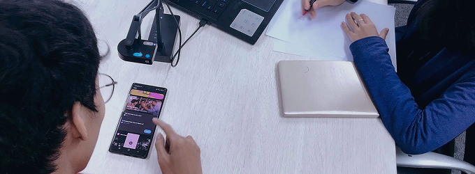 Użytkownik wchodzący w interakcję z aplikacją mobilną, podczas gdy ekspert ds. rozwoju mobilnego robi notatki podczas sesji testowania użyteczności