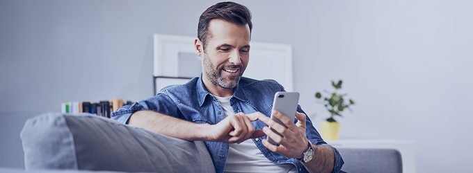 Użytkownik cieszący się płynnym korzystaniem z telefonu w przytulnym salonie