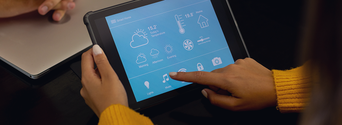 Il residente utilizza il tablet per gestire i dispositivi collegati, come il termostato, le luci e le serrature delle porte, in un'unica app.