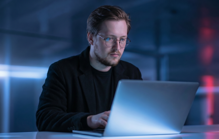 Andrew Nalichaev working on blockchain technology research in a blue-lit workspace.