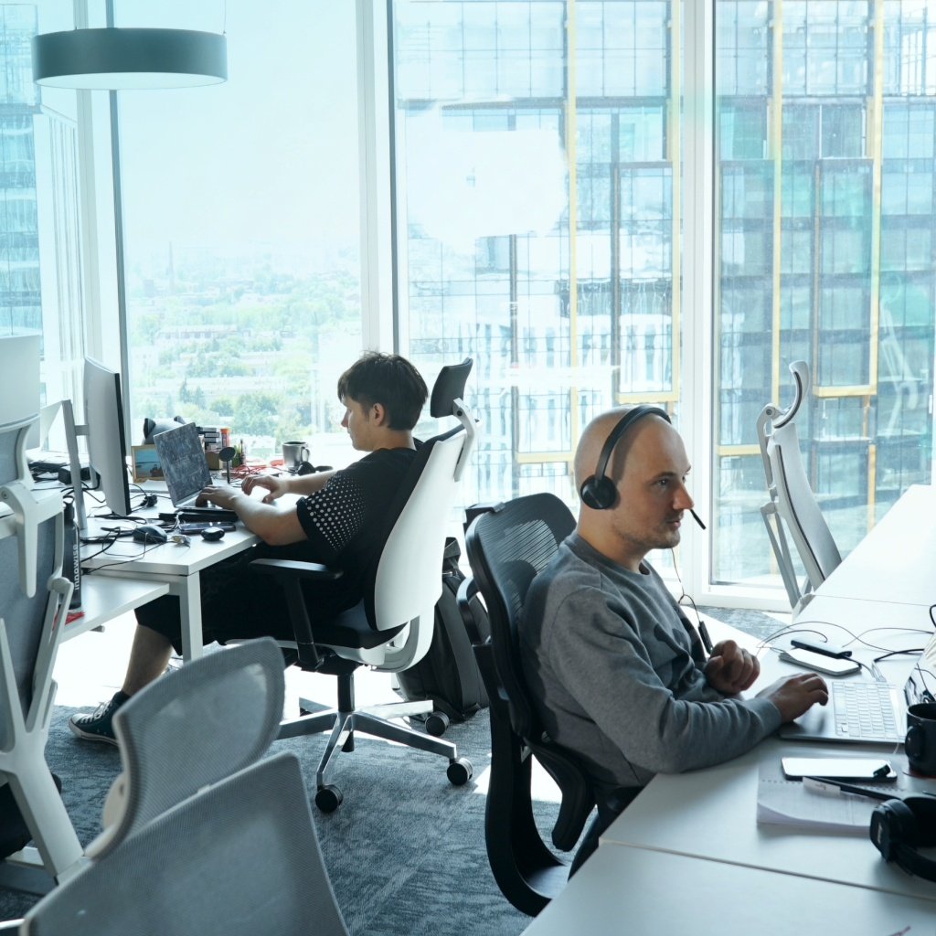 Team multitasking across devices, reviewing tasks and refining projects in a modern office setting
