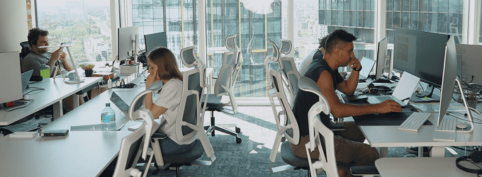 Product team multitasking across devices, reviewing tasks and refining projects in a modern office setting