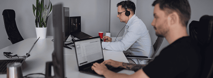 Innowise employees working on a digital product in a quiet office space with headphones and focus on screens