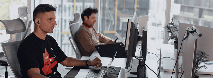 Software development team working on a project in a bright workspace with large windows overlooking the city skyline