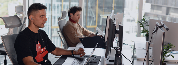 Software development team working on a project in a bright workspace with large windows overlooking the city skyline.