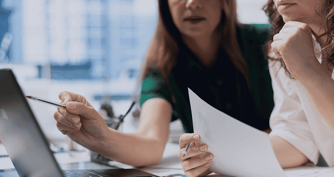 two professionals are discussing implementation strategy, reviewing project documentation, and collaborating on content management system planning.