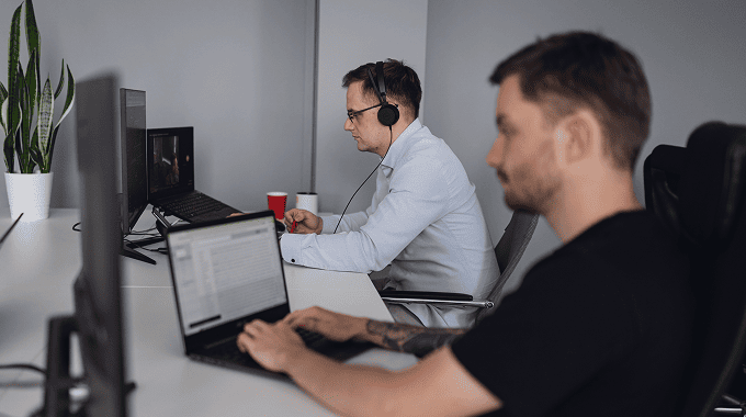 Innowise employees working on a digital product in a quiet office space with headphones and focus on screens.