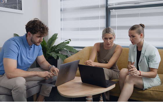 Agile team reviewing project details together on laptops in a casual meeting spot.